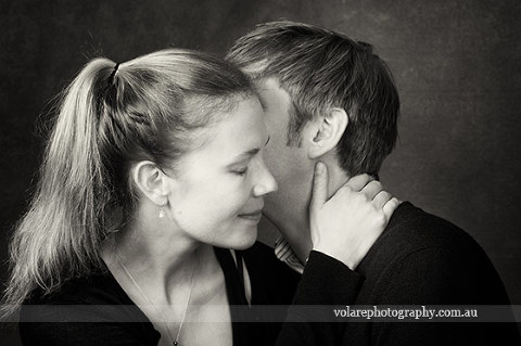 Couples Photography. man whispering kissing lovingly in woman ear. Black and white photography. Relationship portraits studio in Melbourne