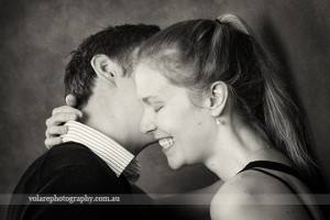 man whispering in woman ear woman lovingly laughing . Black and white photography. Relationship Couples portraits studio in Melbourne