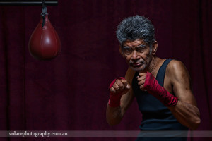 Low key image of boxer father sparring with punching bag studio Melbourne