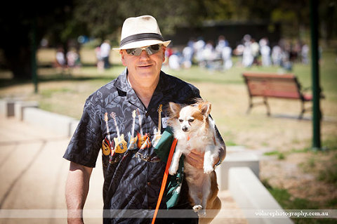 Man carrying dog Victorian Dog Rescue Group Walk around Caulfield Park Christmas Party