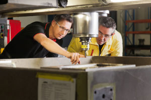 Two men looking at drill and CNC grinding machine industrial photography