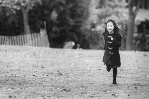 Black and White photograpy image of Happy girl running in park on grass