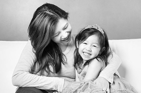 Photograph of Young girl with mother laughing on couch