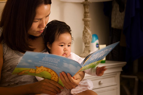 Mum reading bed time story book to baby daughter