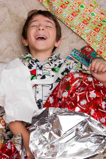 boy having fun and laughing playing with christmas presents
