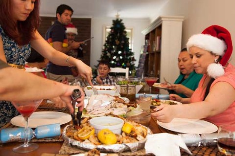 family enjoying christmas lunch around table and serving food