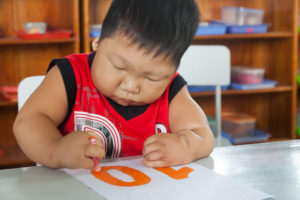 Boy with physical deformities colouring in at school