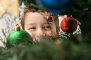 Little boy looking at christmas tree and decorations laughing
