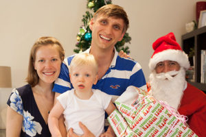 family posing in front of christmas tree with Santa