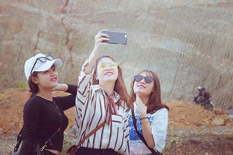 Three girls taking selfie with mobile phone outside
